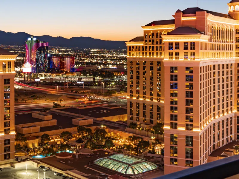Hotel towers lit up at dusk, with city lights and mountains behind